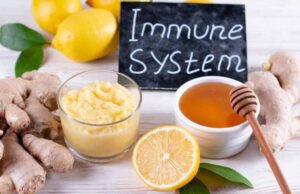 Immunsystem stärken pflanzlich. Arrangement mit Kurkuma, Honig, Ingwer, Zitrone und Kräutern neben einem Schild mit der Aufschrift „Immune system"