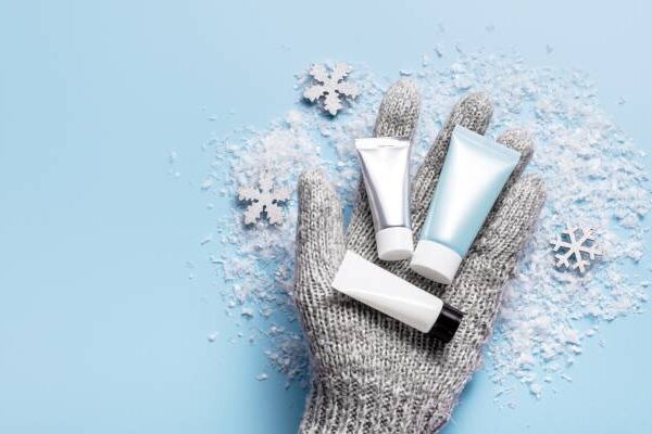 Trockene Haut Körpercreme: Mehrere Tuben auf Handschuh in Winter mit Schnee